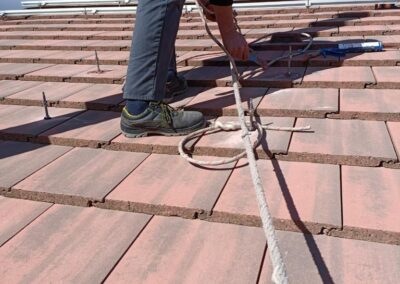 Trabajador instalando placas solares en un tejado con la seguridad reglamentaria